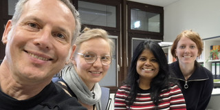 Selfie von Cornelius Schubert, Julia Kurz, Tannistha Samanta und Isabelle Bosbach im Büro. Alle lächeln in die Kamera