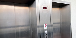 Fahrstühle im Mathetower Auf dem Foto sind die silbernen zweier geschlossener Fahrtstühle zu sehen.